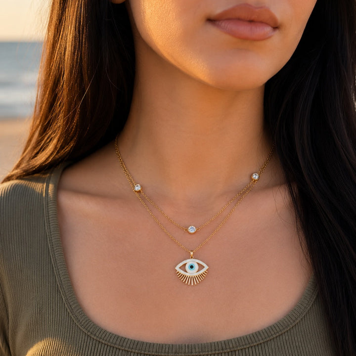 Woman wearing a gold necklace with an eye design outdoors