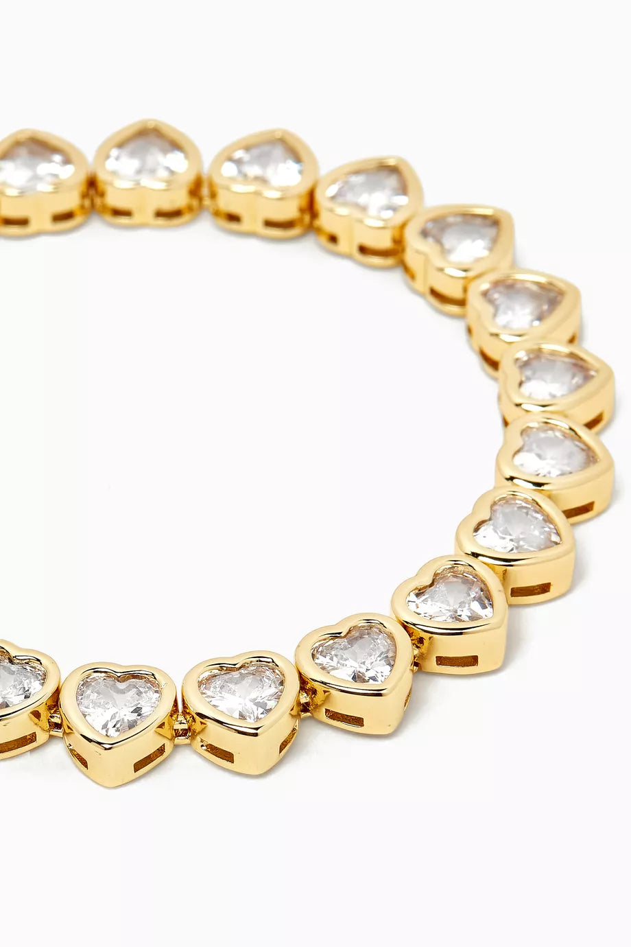 A gold heart-link bracelet with clear heart-shaped gemstones, shown in a close-up circular composition on a white background.