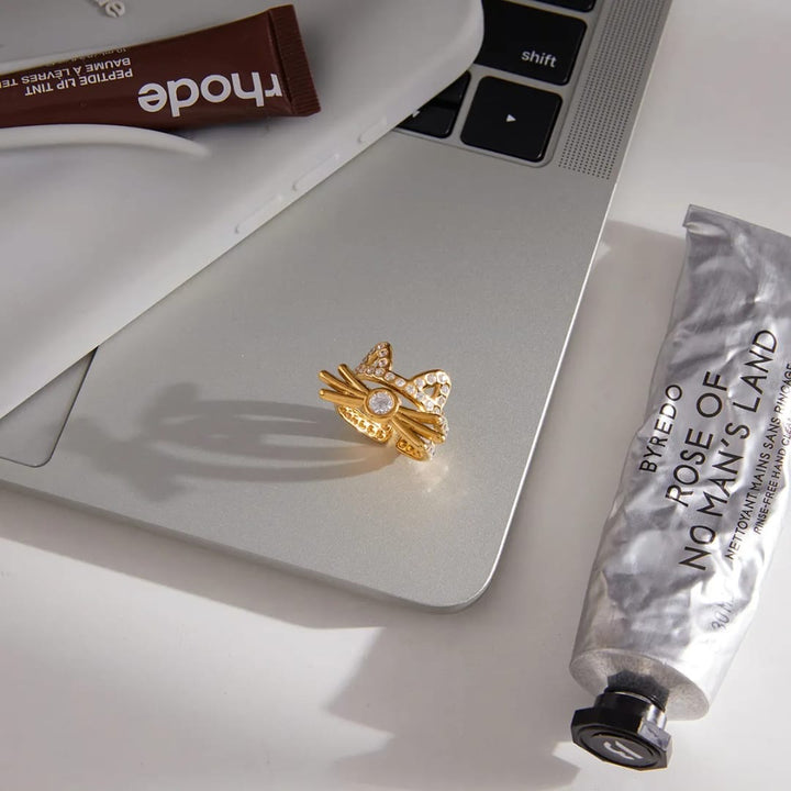 Gold ring on a laptop with Byredo products in the background