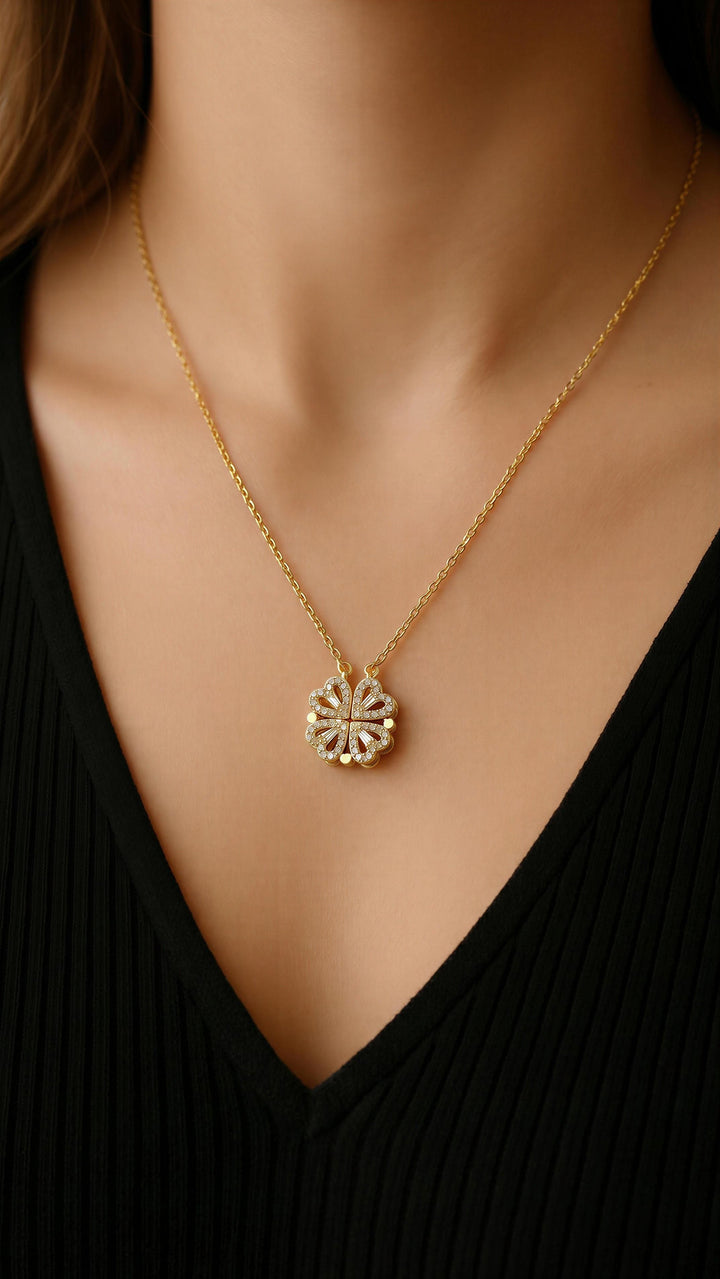 Gold necklace with a sunflower pendant worn by a person in a black top.