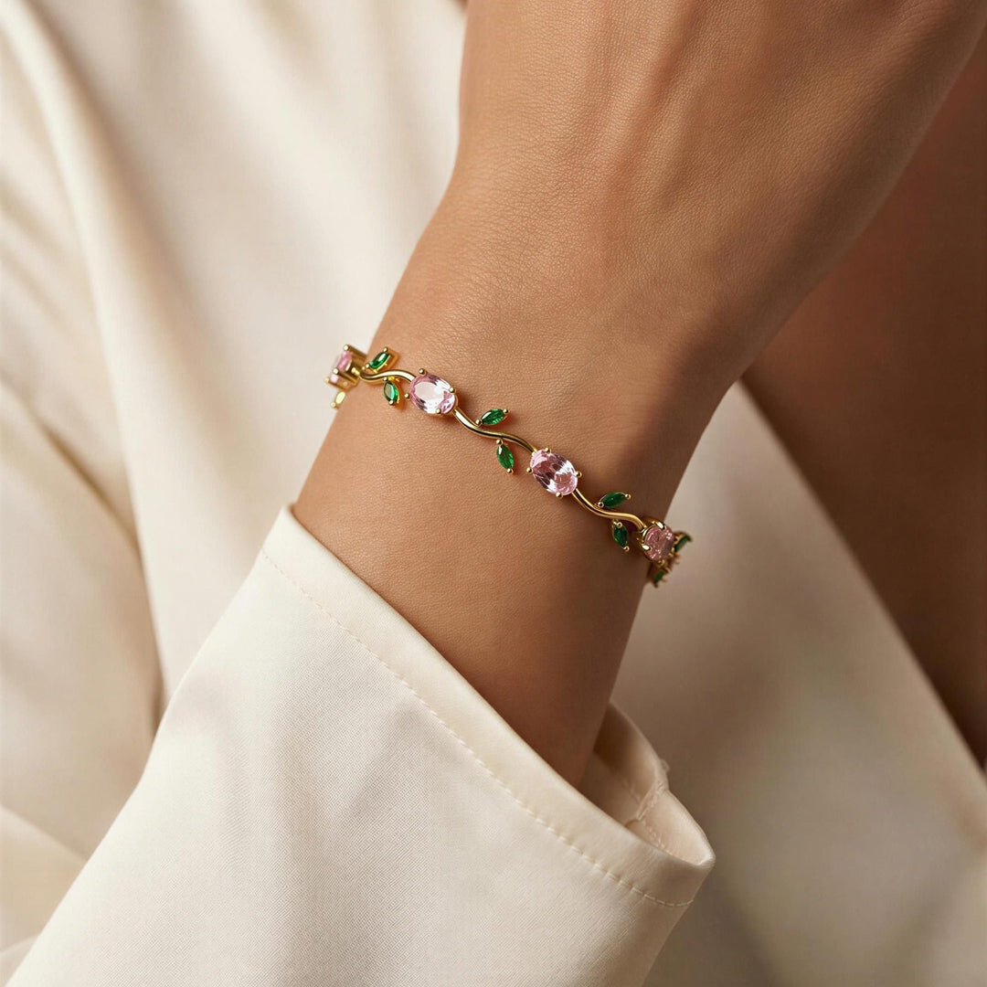 Close-up of a hand wearing a delicate tulip bracelet with pink stones and gold accents.
