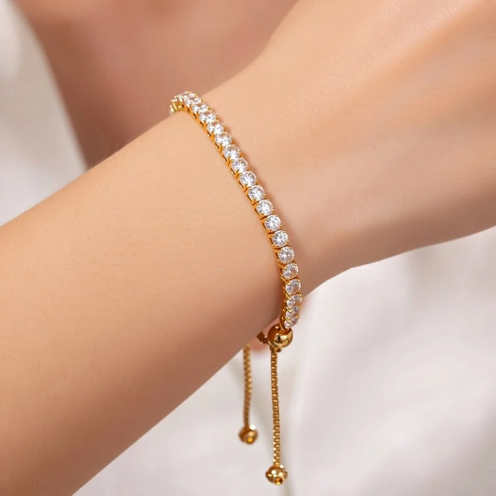 A gold tennis bracelet with clear cubic zirconia stones worn on a person&
