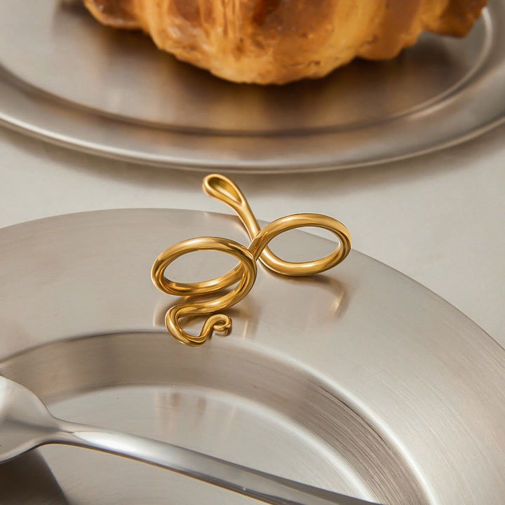 Gold decorative item on a silver plate with a croissant in the background