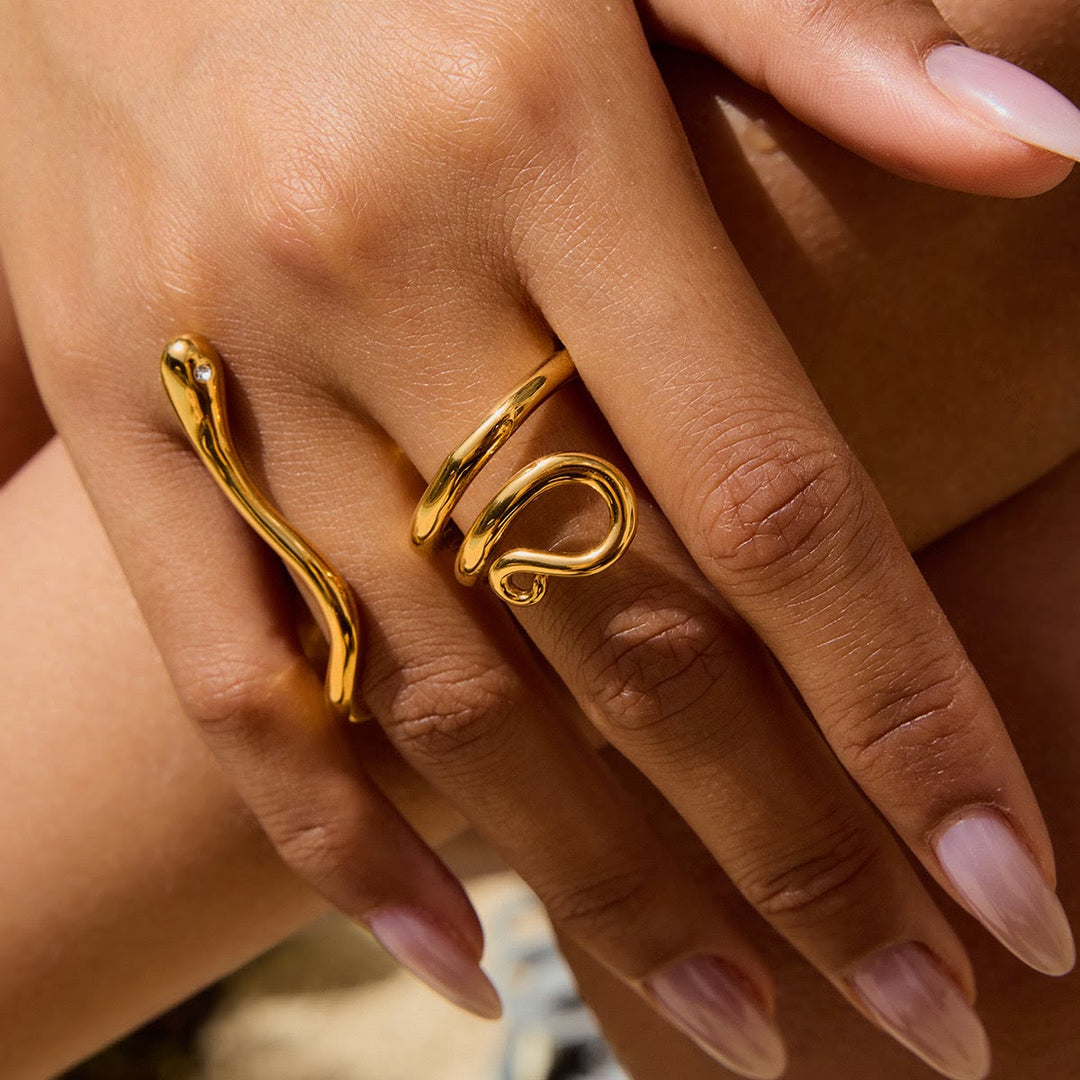 Close-up of a hand wearing two gold rings with a blurred background