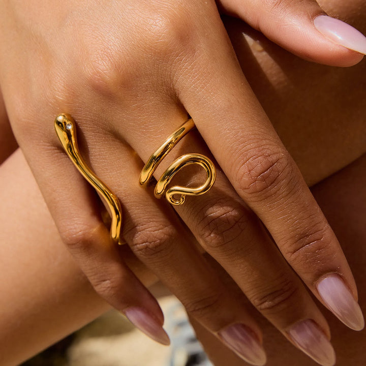 Close-up of a hand wearing two gold rings with a blurred background