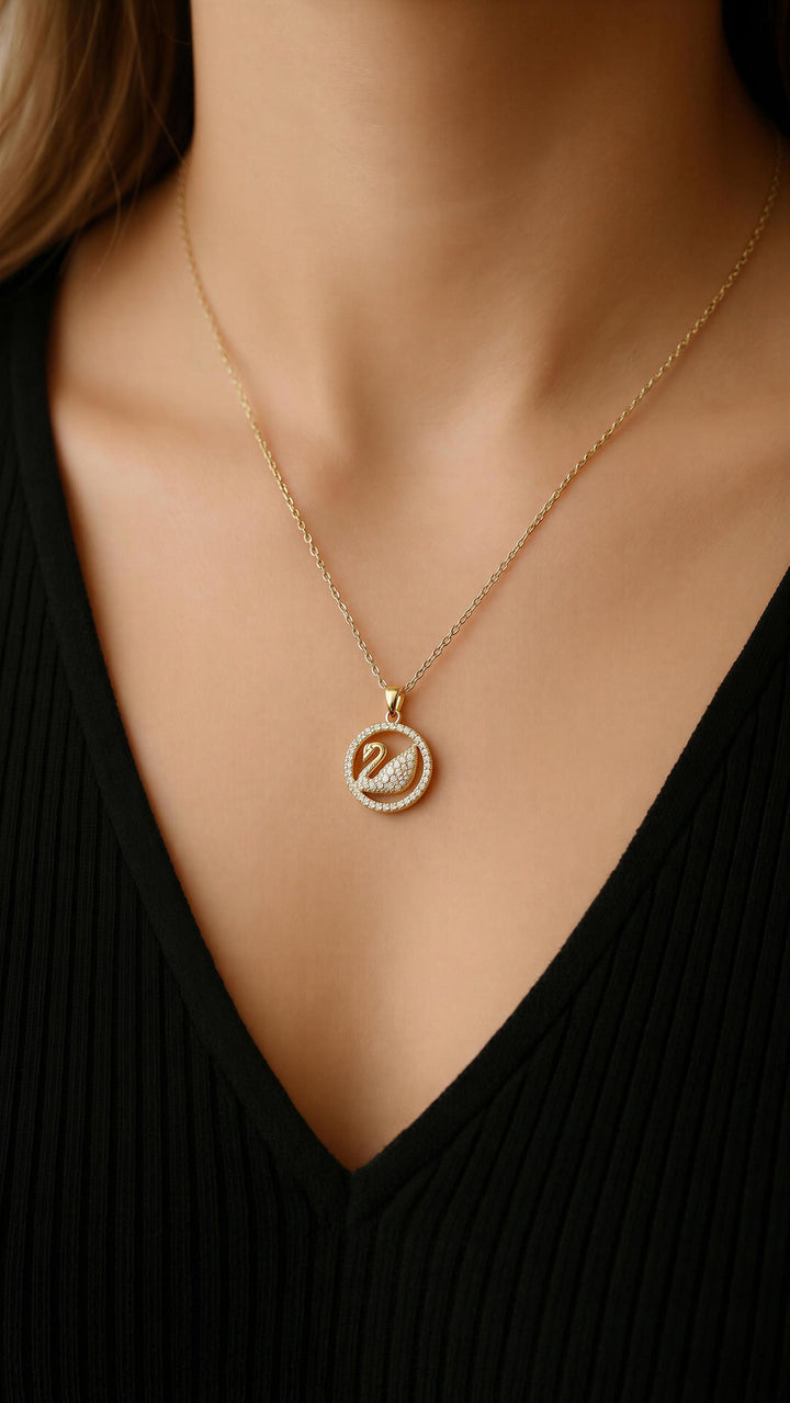 Gold necklace with a pendant on a person wearing a black top