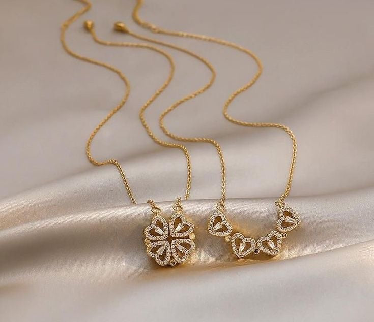 Gold necklaces with heart-shaped pendants on a beige fabric background