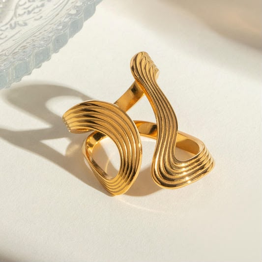 Gold ring with wavy design on a textured surface