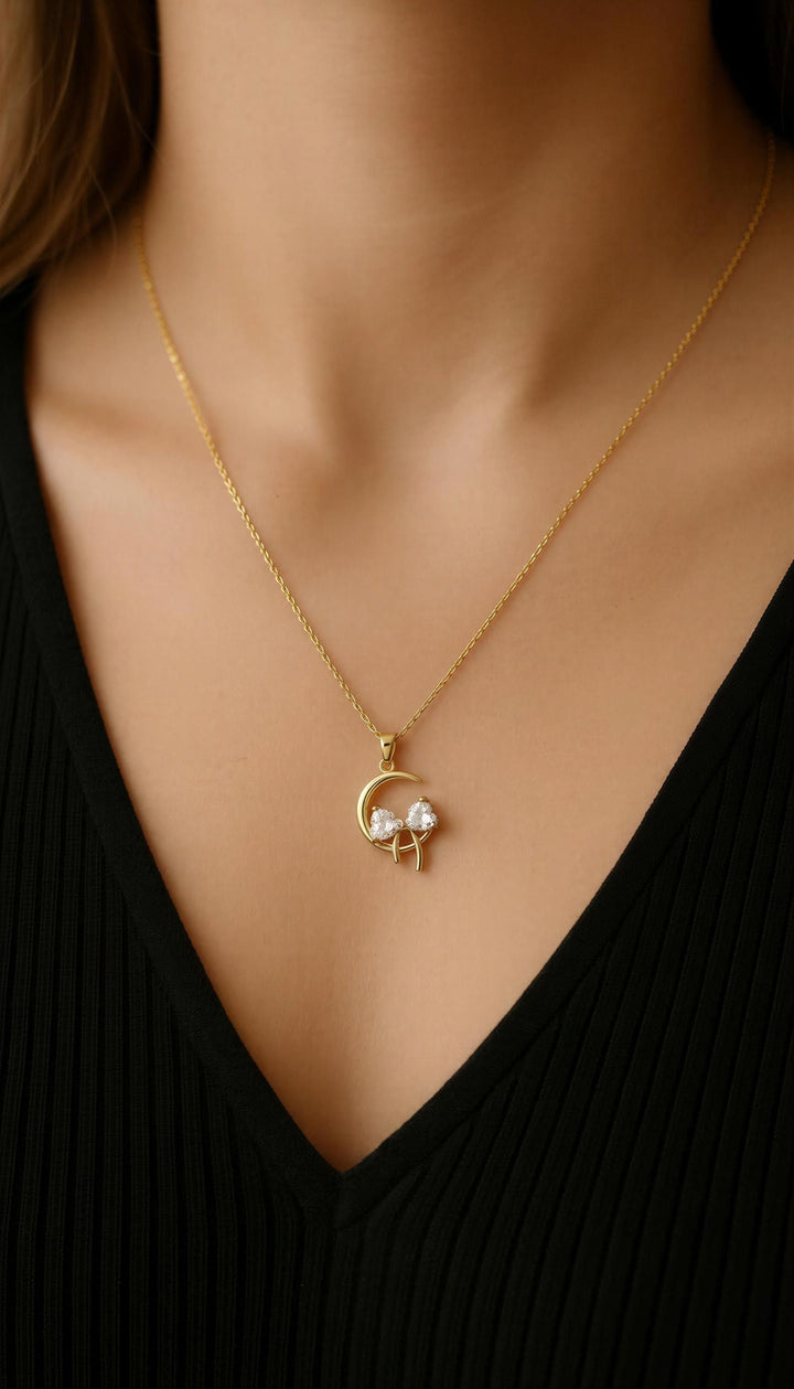 Gold necklace with a pendant worn by a person against a black background