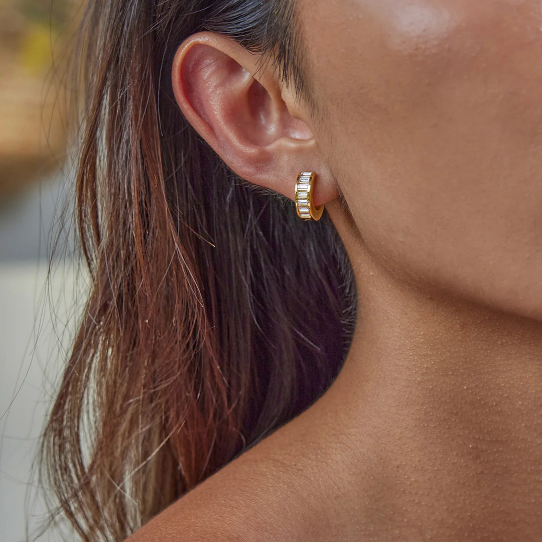 Close-up of a person wearing gold hoop earrings with blurred background