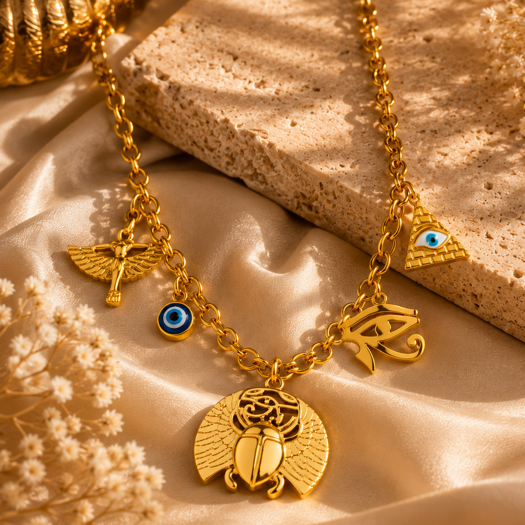 Gold necklace with various pendants on a textured beige surface