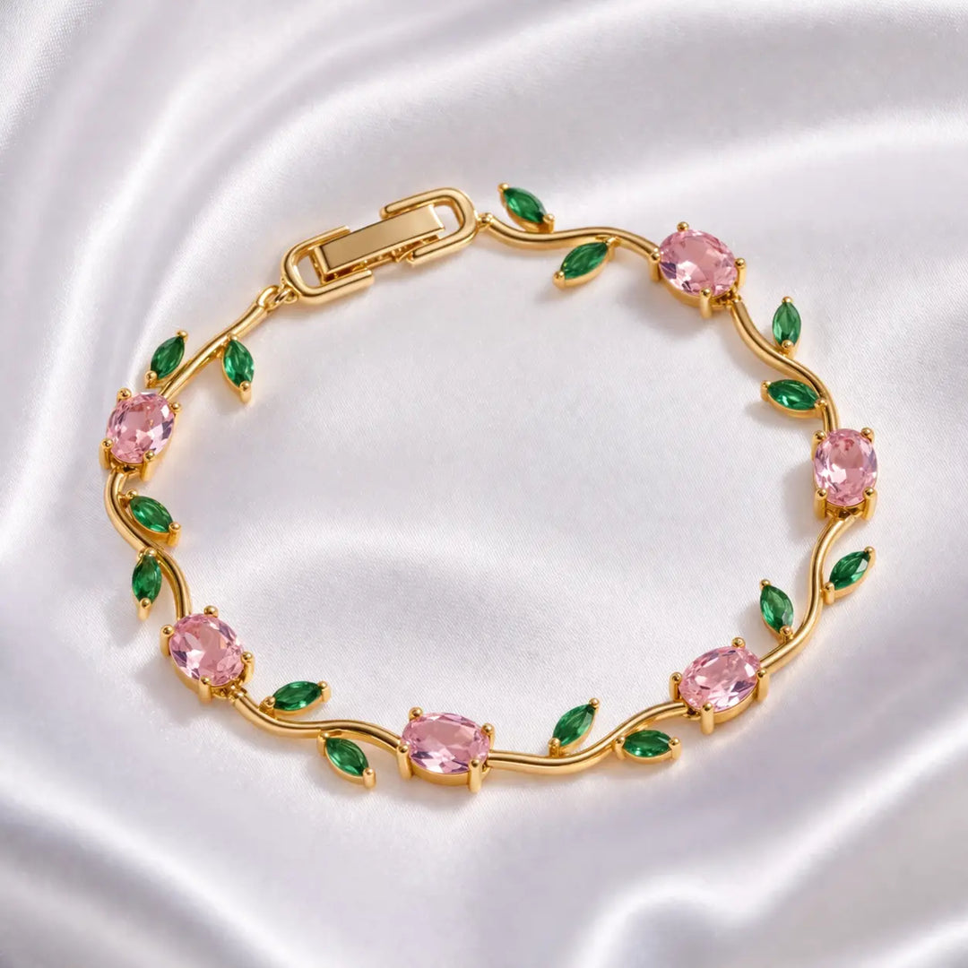 Gold bracelet with pink and green gemstones on a white background