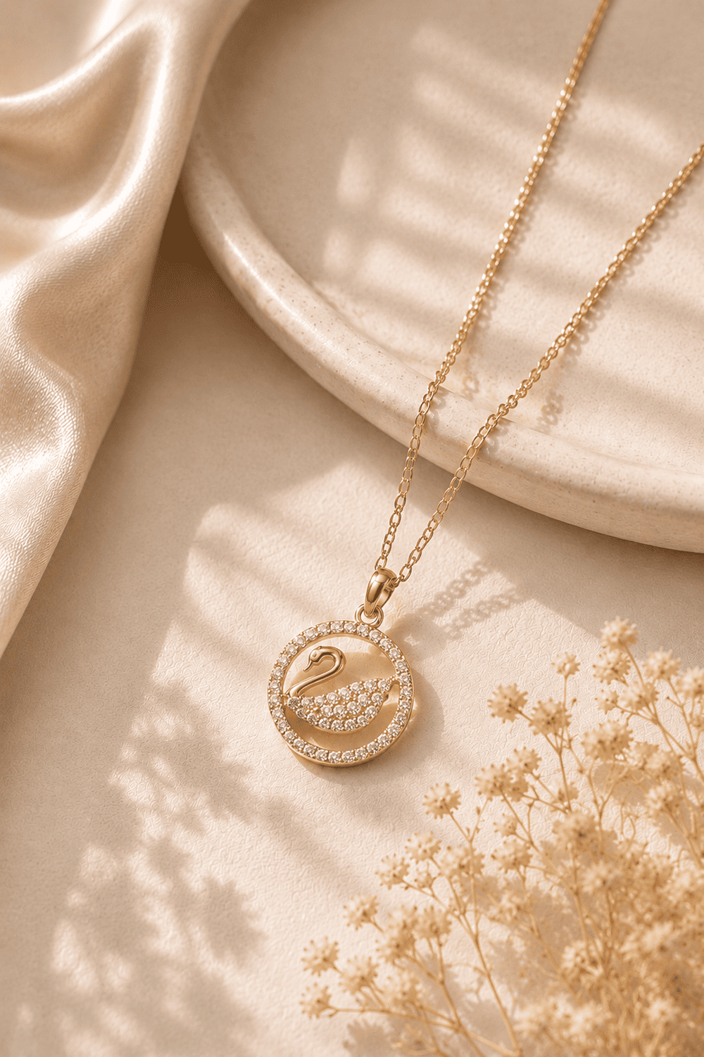 Gold necklace with a swan pendant on a beige fabric background