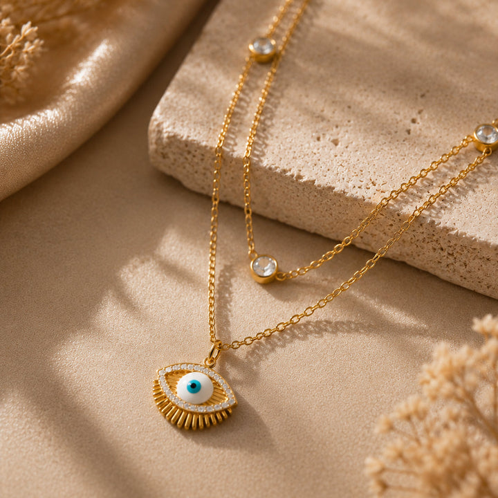 Gold necklace with an eye pendant on a beige surface