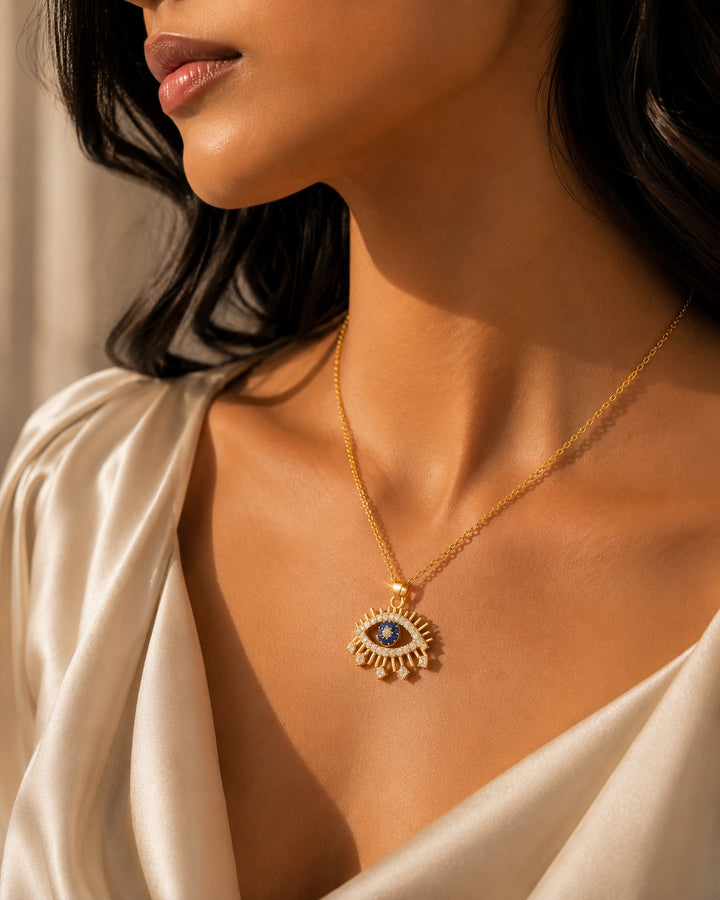 Close-up of a woman wearing a gold necklace with an eye pendant.