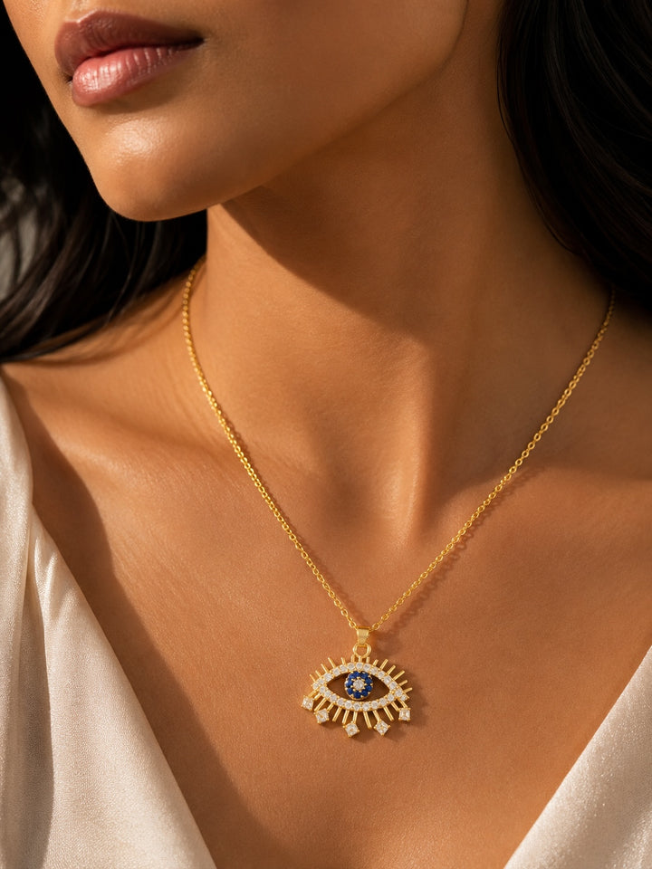Close-up of a woman wearing a gold necklace with an eye-shaped pendant.