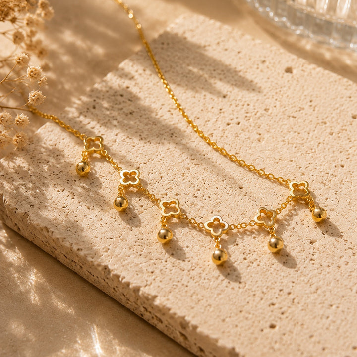 Gold necklace with floral pendants on a textured surface