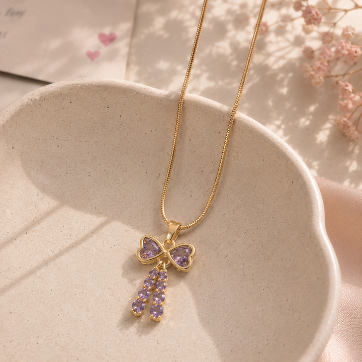 Gold necklace with a butterfly pendant on a textured surface with pink flowers in the background