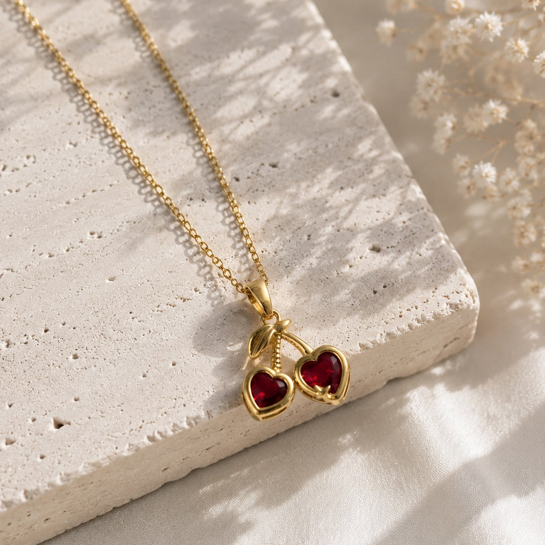 Gold necklace with a heart-shaped pendant on a textured surface