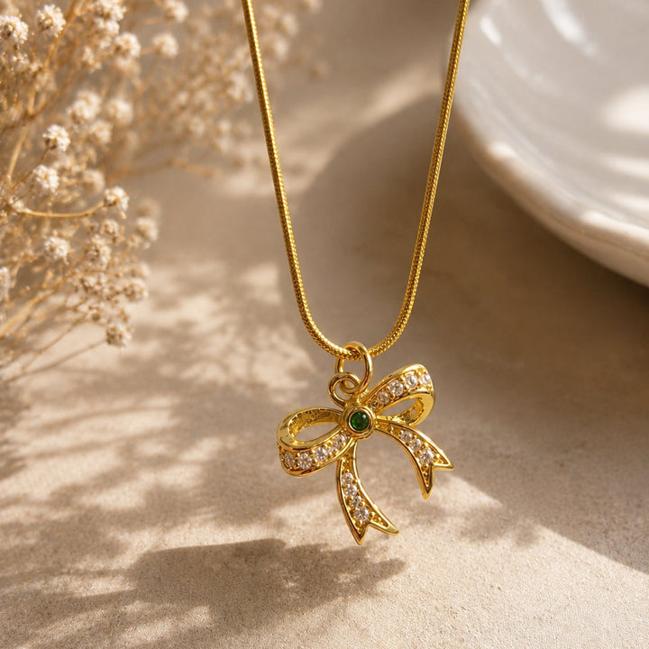 Gold necklace with a bow pendant on a neutral background