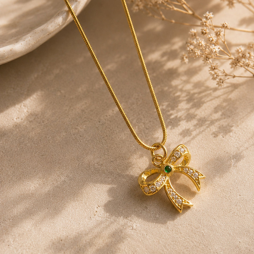 Gold bow-shaped pendant necklace on a neutral background