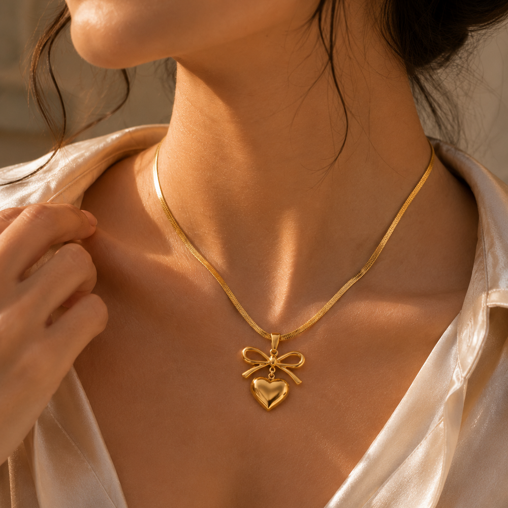 Close-up of a person wearing a gold necklace with a heart pendant.