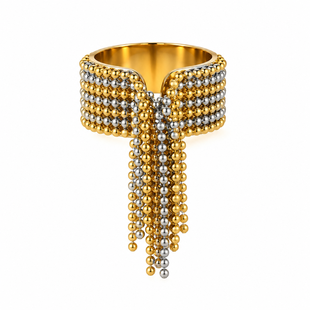 A wide gold-toned cuff ring embellished with rows of small metallic beads and long dangling bead strands in gold and silver, shown on a plain white background.