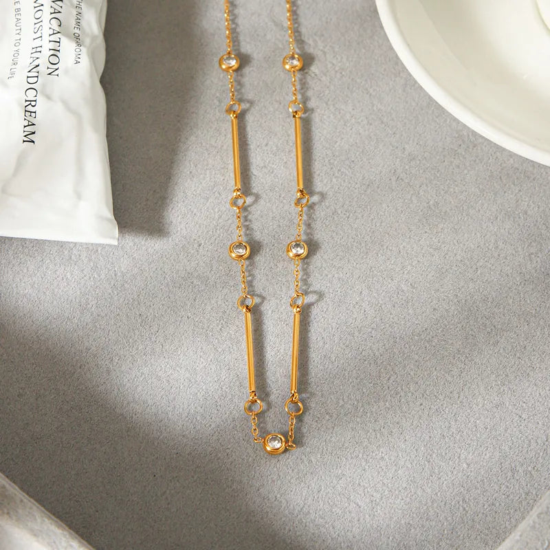 Gold necklace on a gray surface with a white container in the background