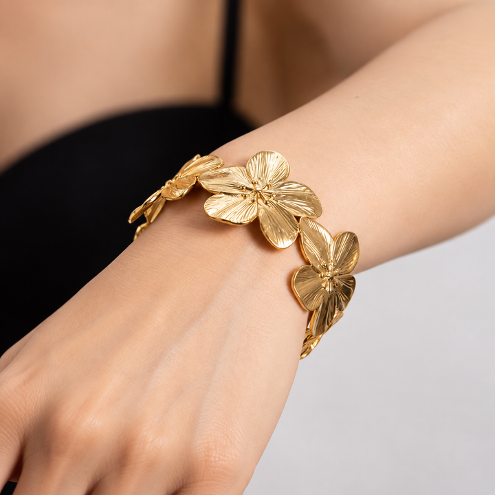 A close-up of a gold flower bracelet worn on a person&