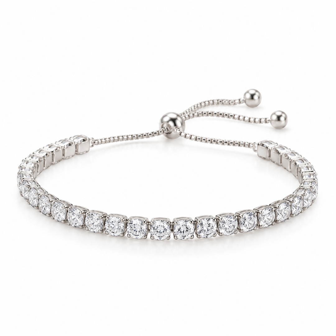 A silver tennis bracelet featuring a row of round-cut clear gemstones in a prong setting, with an adjustable beaded chain closure and ball endcaps, shown on a clean white background.