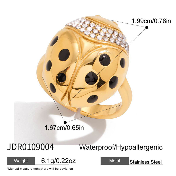 Gold ladybug ring with black enamel spots and a row of clear rhinestones on top, shown on a white background with dimension callouts, weight, and material text.