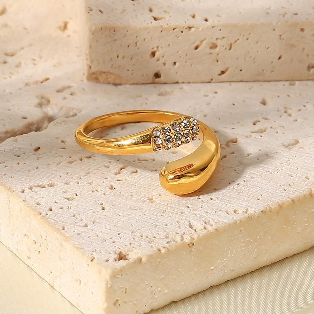 Gold ring with a diamond-like stone on a textured beige surface