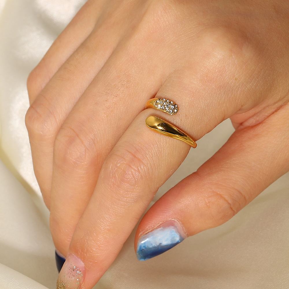 Close-up of a hand wearing two gold rings with diamond accents on a neutral background