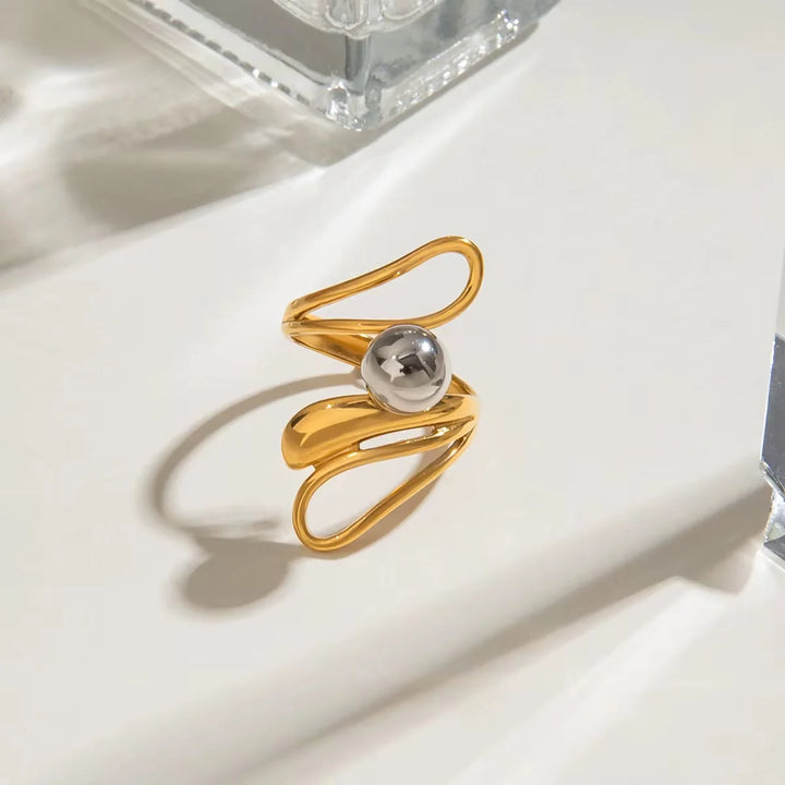 Gold ring with a silver bead on a light surface