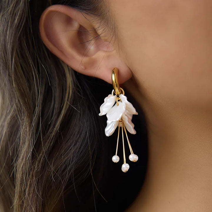 Gold earring with pearl-like stones worn by a person