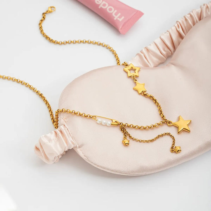 Gold necklace with star charms on a pink satin pillow