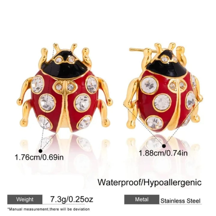 Ladybug-shaped stainless steel earrings with red and gold enamel, clear rhinestones, and dimension labels showing 1.76cm by 1.