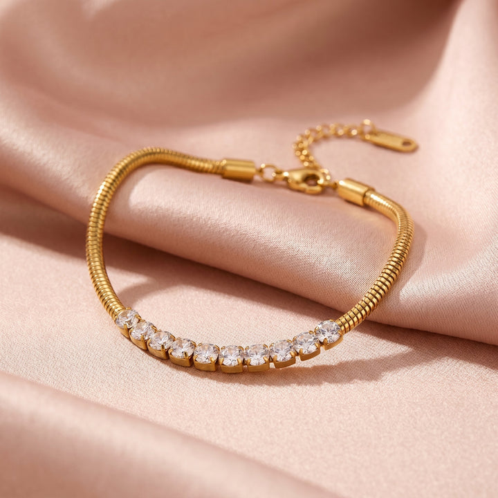 Gold bracelet with diamond accents on a pink fabric background