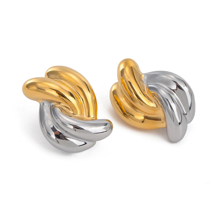 A pair of two-tone metal cufflinks with a twisted, banana-like organic shape, one in polished gold and the other in polished silver, set against a plain white background.