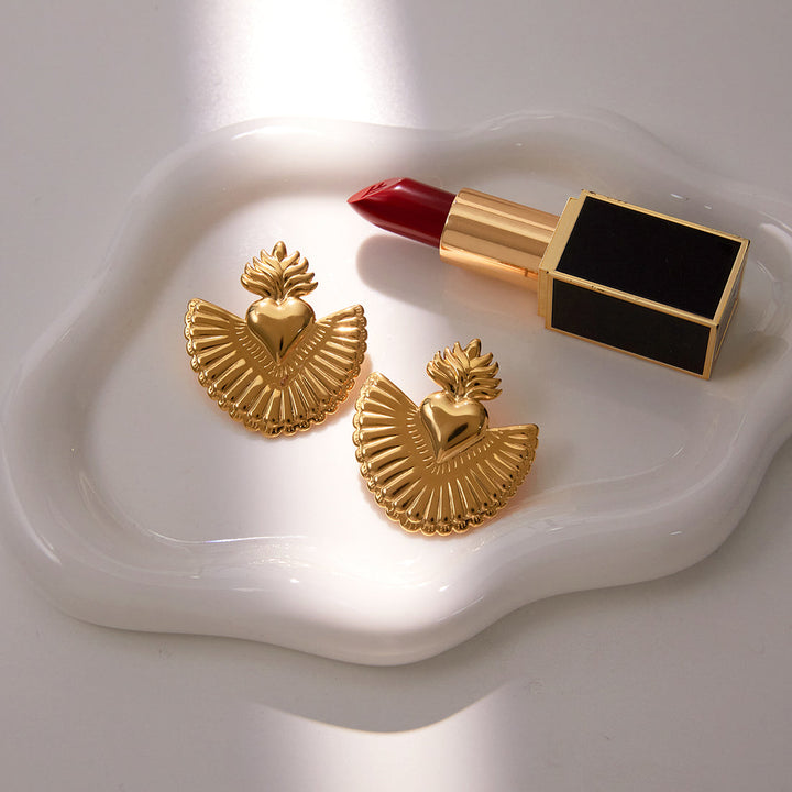 Gold earrings and red lipstick on a white dish