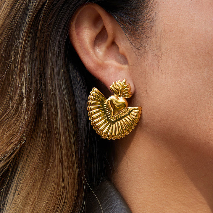 Gold earring worn by a person with brown hair.