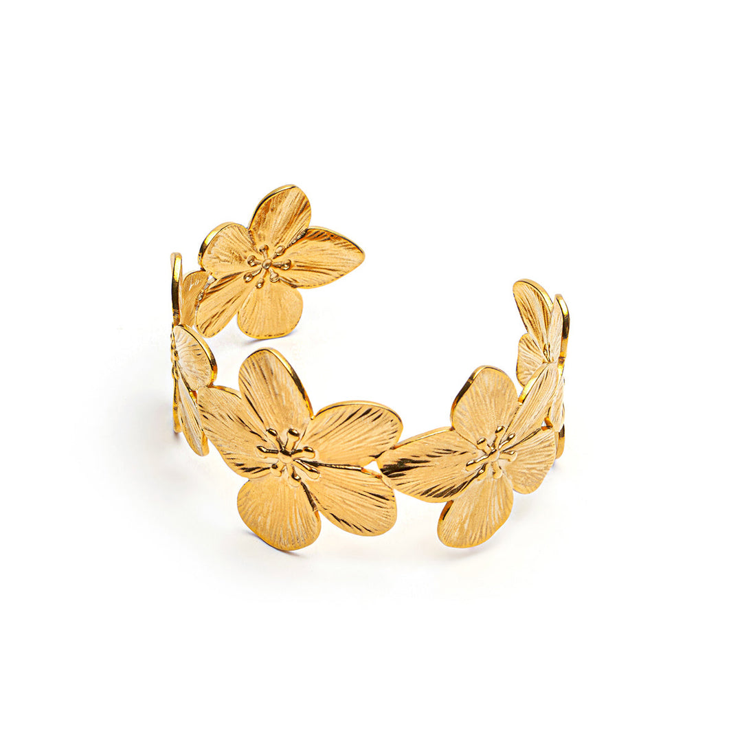 A gold-plated cuff bracelet featuring textured, overlapping plumeria flower motifs, displayed on a clean white background.