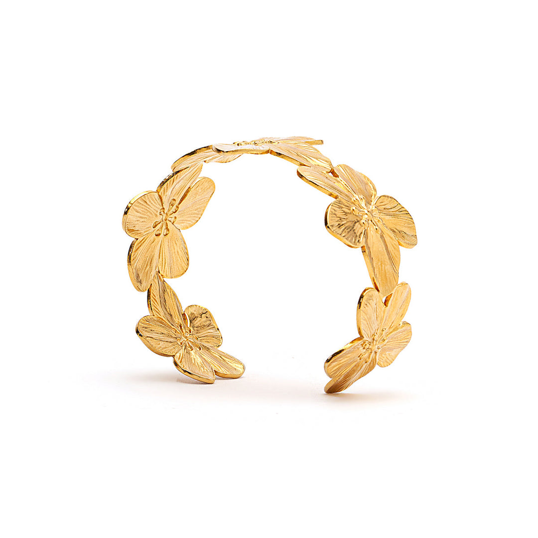 A gold-toned open cuff bracelet featuring five textured flower motifs arranged along the outer curve, photographed on a clean white background.