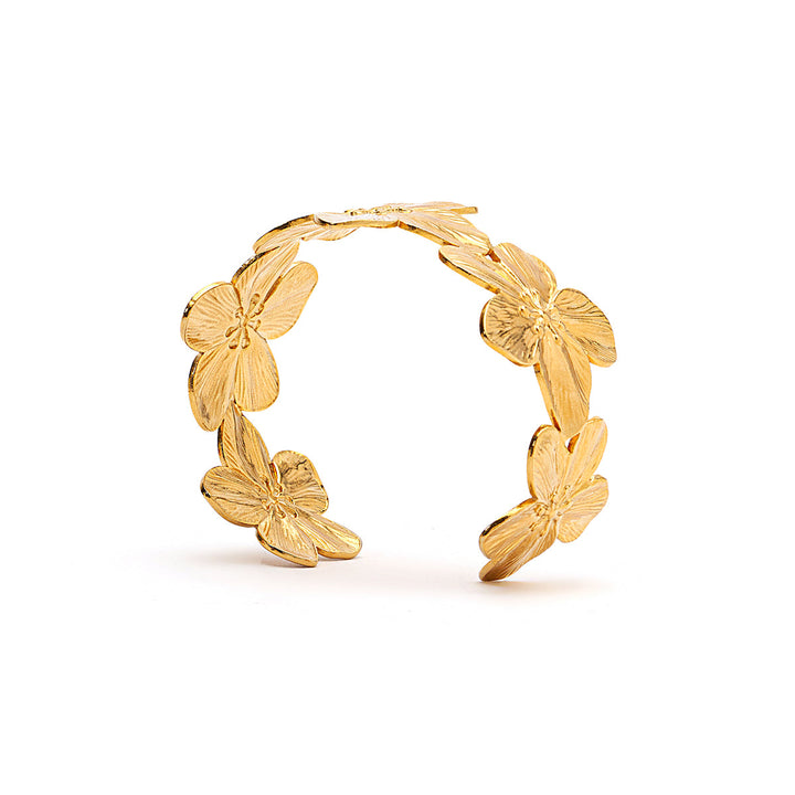 A gold-toned open cuff bracelet featuring five textured flower motifs arranged along the outer curve, photographed on a clean white background.