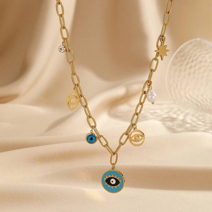 Gold chain necklace with eye-shaped charms on a beige fabric background