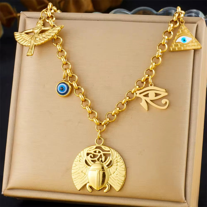 Gold necklace with various charms on a beige box