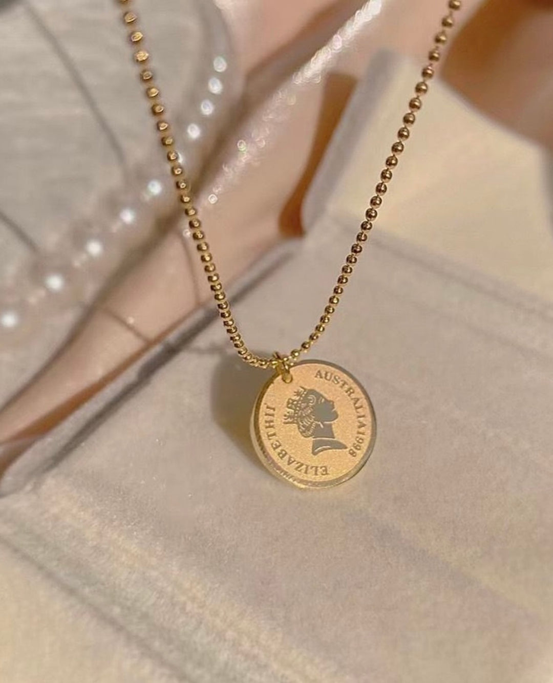 Gold necklace with a round pendant on a textured surface