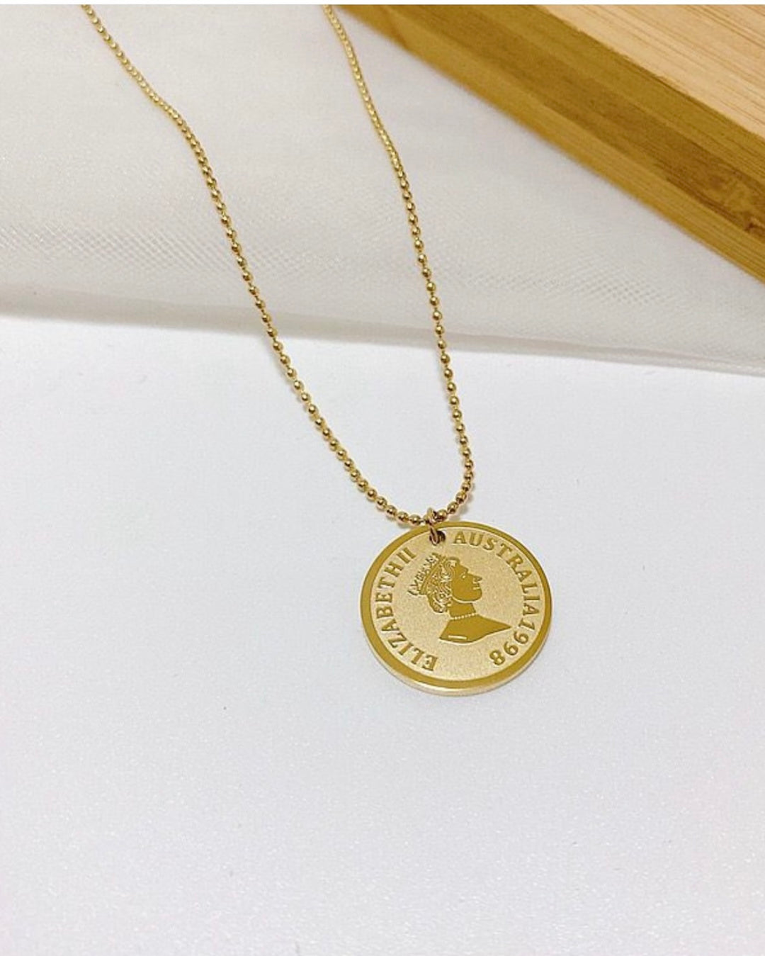Gold necklace with a round pendant on a white surface