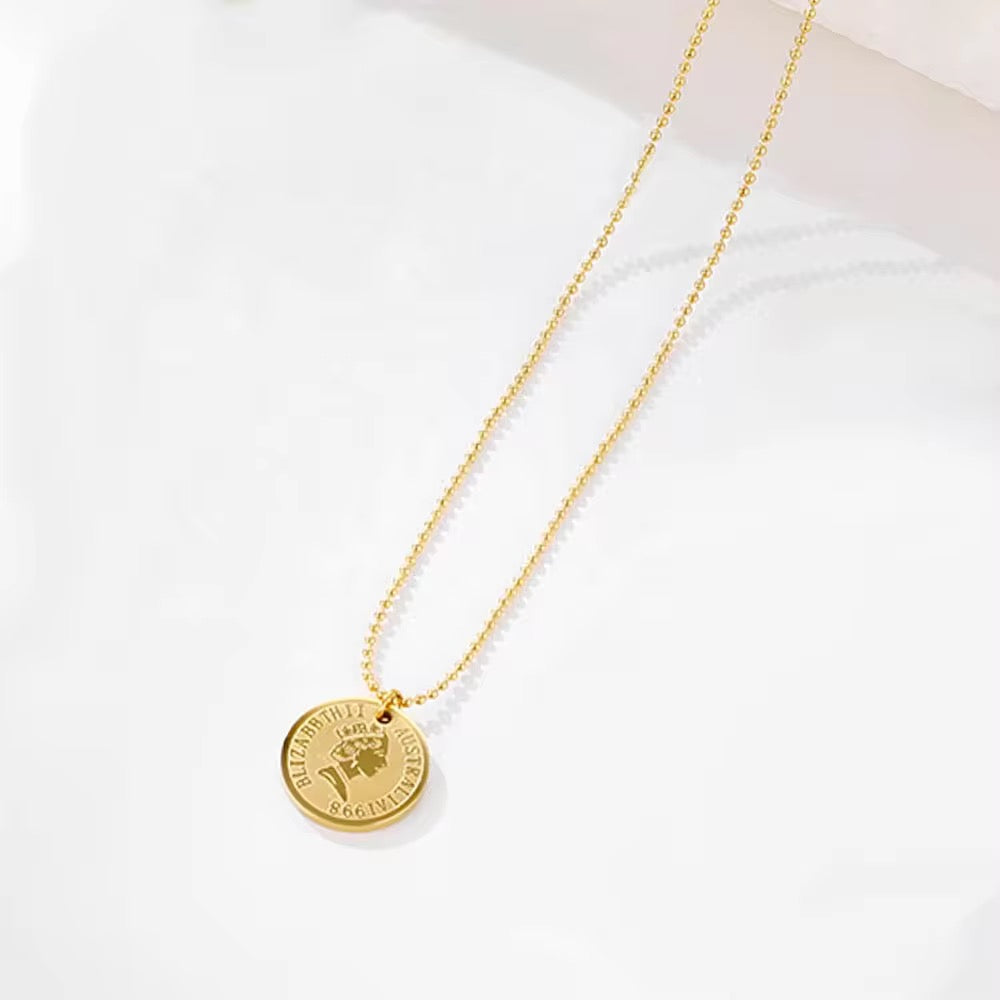 Gold necklace with a round pendant on a white background