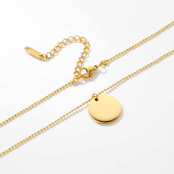 Gold necklace with a round pendant on a white background